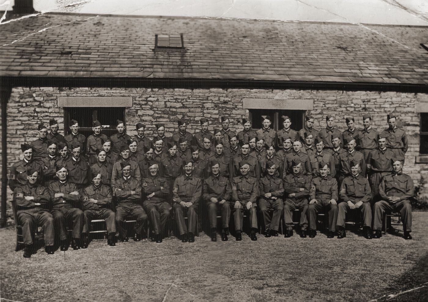 Coll: several copies at postcard size in the community. Copied 1999. This version not as clear as one from a 120 neg.Members of the Alston Moor Local Defence Volunteers, later to become the Home Guard, pictured in the yard of the old primary, (Salvin), school at the beginning of the second world war. (See numbering diagram.)Notes form Billy Renwick, The Cottage, Nenthead Road, Alston, taken 5th November, 2005.Front Row1.Percy Thompson of Leadgate. 2. Matt Todd, a gamekeeper for the King-Websters of Wanwood. Lived at The White House Alston Townfoot. 3.Fred Birkett, father of Harold Birkett of Henderson's garage. 4. Bertie Bell, worked for Craigs as a mason. 5.Tom Snowden Snr. worked for both Craigs and Keartons builders- came from the Horse and Wagon. 6. Fred Kearton- of the building firm, (see Theatricals). 7. Major Johnson- cavalry soldier in first warlater managing repairs for the Greenwich Hospital & living at the Old Manor. 8. Tommy Haldon, Haldon's Mill family, musician (see Theatricals), shop at Townfoot. 9.? Baker a WW1 officer from Nenthead 3 daughters.one =Joan. 10. Unknown. 11. Ernie Murray, an Alston postman who lived in King's Arms Lane. 12. Tommy Thompson from Sandhill- worked for Craigs builders. 13. Fred Edgar from The Butts, who also worked for Craigs. Central row14. Jack Amos of High Bayles, (acc. John Place)NOW Though to be Willie Holmes, draper- acc John Holmes. 15. Cliff Brookes- in charge of  and living by the gasworks, (which always had 2 workers) he went off to the gasworks at Kirby Stephen when Alston's closed. 16. Geordie Hind, Alwyns dad, (See Childhood, Micky & Minnie Mouse). Geordie had left Alston Moor to mine down by Stoke. He and Billy Renwick came back on Christmas army leave via Crewe in 1945. George died on that leave. 17. Unknown. 18. Gyp Cousin- always "Little" Gyp Cousin- worked at Foundry in war, (see Foundry files), smoked a pipe. 19 Maurice Lee- brought up at the Turks Head- Lilly Pattinson was his auntie. (See him in WW1 uniform on horseback by quarried face and with a bull working over towards the Tyne- images from Grace Renwick nee Bramwell., his niece). 20. Cliffy Jackson, David's dad- worked at Henderson's. 21.  Tom Hetherington, Mary Jeffries&rsquo; brother- he came from Ryhope and worked in the bakehouse for Birketts. 22. Reg Spark, killed at Arnhem, lived on Station bank- his father drove a coal wagon for Dickinsons on Low Byer. 23. Percy "Gaffer" Renwick. once drove for Hendersons & eventually took the top pub, The Swan. 24. Reg Renwick, Billy's uncle. (Photographed on a motorbike with his son, in The Morton/Maltings Square. Worked for the Greenwich Hospital and Keartons but in the war at Rotherhope Mine. In common with many of the workers there his transport was, "a little bare necessity of a motorbike"- pedalling often being needed.25. Harold Lancaster- from the Mill family- ? on front line with his brother on the 1897 mass photo? His father had lived at and been caretaker at the Town Hall. 26. John Harrison- lived at the Workhouse Cottages. 27. John Smith, a farmer from Slaggyford. 28. Frank Pickering, a mason who built Billy's home, The Cottage and Dale Cottage next door in about 1919. 29. Eric Davidson who lived in the upstairs part of South View, Nenthead Road. He worked as a platelayer for the railway & features wirh Arthur Harrison on the image, Rail points snow.tif. 30. Alan Struthers, older brother to Alec.31. John Rawlings, bank clerk. 32. Willie Gregg worked for Keartons and features in the 2 bottoms image with Fred Renwick- building the observation post at Fairhill "ObserverCorps Tower.tif"  33. Bob Allen - a keen boxer- trained young fighters- became a sergeant in the Home Guard- drove a 2 ton parcel delivery truck from the railway station. 34. ? Wilson. worked at the Foundry & lived at the Ewe & Lamb/ Royal Oak. 35. Joe Raine, farmer. 36. Jimmy Cousin, a mining footballer who eventually went to Africa, mining for diamonds and gold. 37. John Martin, the "roadman" whose office was upstairs opposite the Police Station. 38. Harold Lowe. Harold's brother ran a cattle wagon. He and Billy Renwick were half way through building a fresh cattle body when a siren went off. Back to Billy's home they went. Billy's mother announced, "There's a war on." The siren had been run by Dr. Dalgety, the GP, who was thought to be over reacting! Meanwhile Mr. Lowe discovered that if he bought an American wagon the War dept. wouldn't commandeer it. So bye bye Commer, hello Chevy. (To see the Chevy, with the youthful Gordon Blackstock, see the image HeslopBlackstock.tif. ) 39. Arnold Bell, a farmer at The Bayles. 40. Wallace Millican Snr. Whose house opposite St. Augustines church would be demolished to form Church Road in the late 50s. Back row41. ? Ward, a joiner from Nenthead. 42. Jasper Stephenson- farmed at High House Nenthead but later took a warmer farm at Melmerby. 43. ? Armstrong from Grassfield, Nentsbury. 44. Willie Lee another one-time gamekeeper for the King-Websters at Wanwood. He lived by the Brewery Bridge and had a pair of Border Terriers. 45. Jeffrey Beadle from The Butts. Jeffrey played piano and melodian music around the pubs- "He never needed music. He'd just ask, "How does it gar?"" 46, Tom Jackson, (another one), One of Squire Jackson's lads, he worked at the Hartside Top barytes mine. 47.? Robinson- who married Charlie Martin's wife. (Charlie himself was defined as a) an Italian, b) a clock repairer, c) lived at the house beside Rotherhope Mine and d) a hard case!) 48. Robbie Raine, the Randalholme Ram, who married Margaret Seymour of Black House- Randal Raine's dad. 49. Walton Burrell, Dorothy Blackstock's brother- he came to Alston to take the top pub. 50.(lower figure), Gordon Beresford lived at Nenthead & worked as a clerk for the Anglo-Austral Mining Co..He married Jack Douglas's sister. 51. John James Armstrong father to Dulcie Fraser and legendary butcher- worked for Biggs then took over his business. 52. Gordon Edgar, oldest son of Fred, #13. 53 Tom Snowden Jr. The Alston Comic whose size 14 shoes would resound through dances at the Halls. 54. Willie Nicholson, projectionist at the cinema- he's still around, (2005) in Kirby Stephen. His father was Newt Nicholson who worked for and was a great friend of cobbler Jack Varty. (See Varty image. also on a wagonette.55. Harold Dickinson, (still around in 2005. he was Kearton's "small contracts manager", he told a tale of the Home Guard rattling a tin full of pebbles to sound like a machine gun while they were practicising, 56. Edwin Biggs, son of butcher Albert, the man who killed beast in the slaughterhouse in Back O' the Burn. 57, Henry Raine, Willie's dad- from Randalholme.(many images). 58. Willie Martin- lived at the last house on the left on the Nenthead Road. 59, John Harrison of Aimshaugh - he married Tommy Thompson's daughter.
